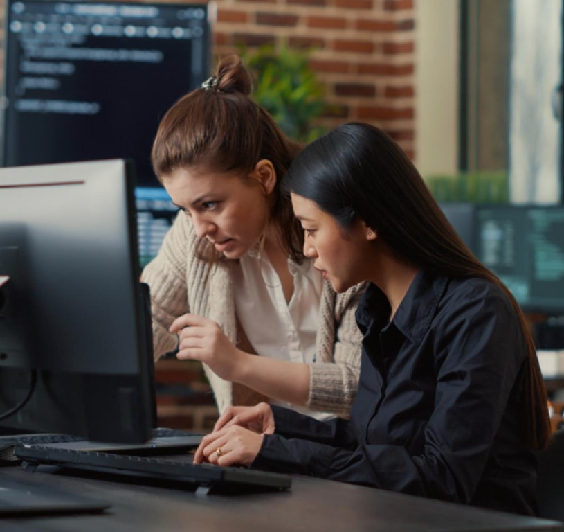 Two colleagues reviewing work at a computer
